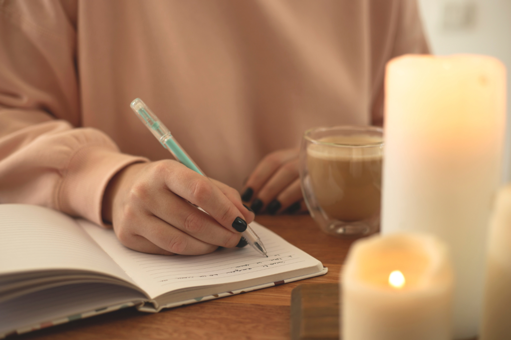 close up image of a woman journaling with candles burning around her