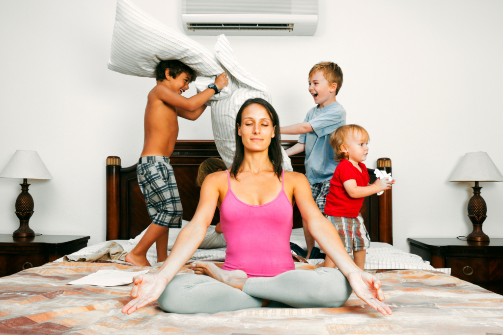 woman meditating while her kids are playing behind her
